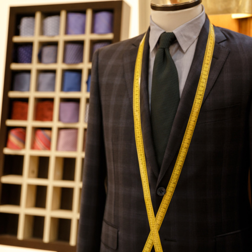 Photo of checkered men suit jacket on hanger with measuring tape on it